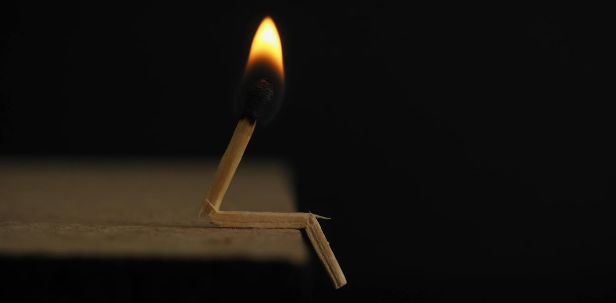 lighted matchstick on brown wooden surface