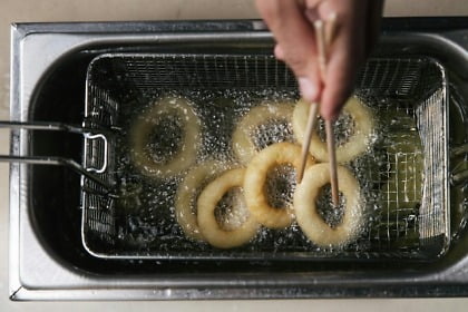 photo of a person s hand cooking onion rings