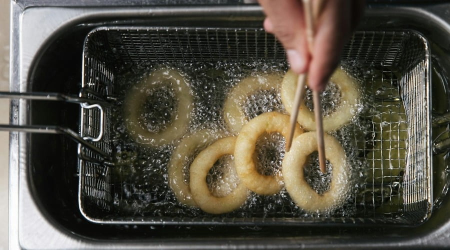 photo of a person s hand cooking onion rings